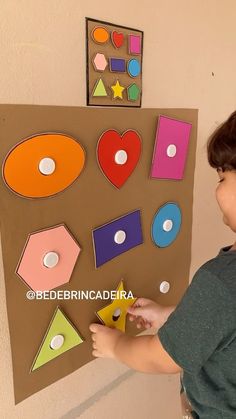 a young boy is making a paper cutout with shapes and numbers on the wall