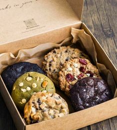 a box filled with cookies and muffins on top of a wooden table