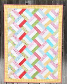 a colorful quilt hanging on the side of a wooden fence with text overlay that says,