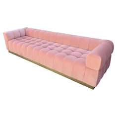 a pink velvet couch with gold trimmings on the legs and back, sitting in front of a white background