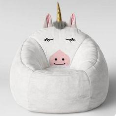 a white unicorn bean bag chair with a pink nose and gold horn on the top