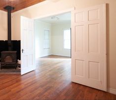 an empty living room with wood floors and a fire place in the corner between two doors