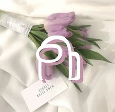 purple tulips are on the white sheet with a name tag attached to it