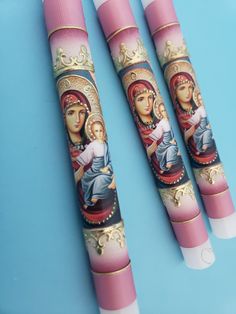 three pink crayons with images of virgin mary and jesus on them are sitting on a blue surface