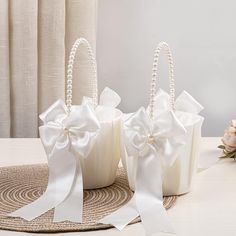 three small white baskets with bows and pearls on the handles are sitting on a table