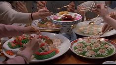 several people are serving themselves food at a dinner table with chopsticks in their hands