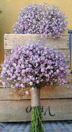 purple flowers in a vase sitting on top of a wooden crate next to a planter