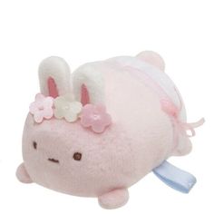 a pink stuffed animal with flowers on its head and ears, sitting in front of a white background