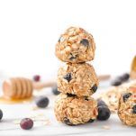 three oatmeal cookies stacked on top of each other with blueberries and honey