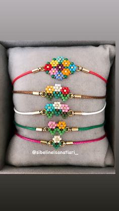 four bracelets with different colored beads on them in a gift box, one has a gold - plated clasp and the other is made out of leather