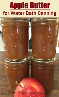 three jars filled with apple butter sitting on top of a wooden table