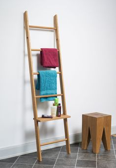 a wooden ladder leaning against a wall with towels on it next to a step stool