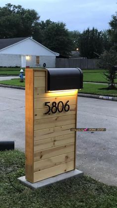 a wooden mailbox sitting on the side of a road next to a grass covered field