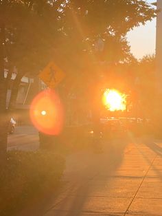 the sun is setting over a street with cars parked on the side of the road