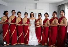 a group of women standing next to each other wearing red and gold sari dresses