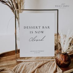 a desert bar is now closed sign next to a vase with dry grass in it