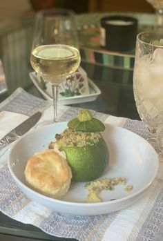 a white plate topped with green fruit next to a glass of wine on a table