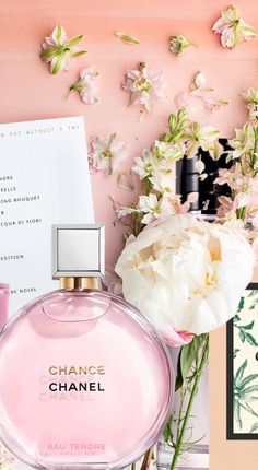 chanel perfume bottle next to flowers on pink background