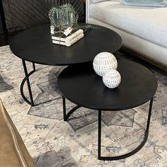 two black tables sitting on top of a rug in front of a couch and coffee table