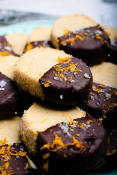 chocolate covered cookies with orange zest sprinkles on a glass platter