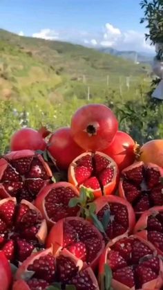 pomegranates and other fruits are piled on top of each other outside