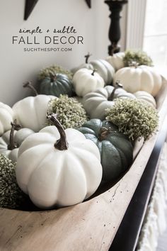 white and green pumpkins are arranged on a wooden shelf