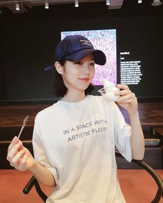 a woman holding a fork and spoon in her hand while wearing a t - shirt that says in a space with artistic flow