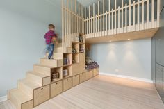 a child climbing up the stairs in a room with wood flooring and white walls