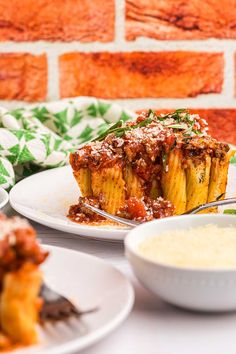 two plates with lasagna casserole on them next to a brick wall