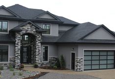 a large gray house with two garages on the front and one car door open