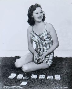 an old photo of a woman sitting on the ground with some cards in front of her