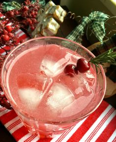 a close up of a drink in a glass with ice and cherries