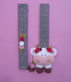 two cow brooches are sitting next to each other on a pink surface with black and white designs