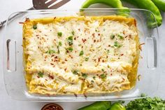 a casserole dish with cheese, sauce and green peppers on the table next to it