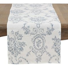 a table runner with blue and white floral designs on it, sitting next to a wooden bench