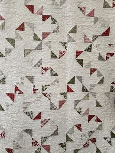 a white quilt with red and green triangles on it