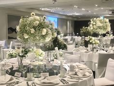 the tables are set with white flowers and silverware