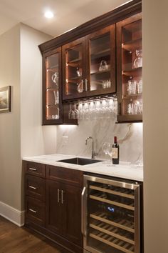 a kitchen with wooden cabinets and wine glasses on the counter top in front of it