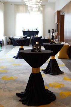 tables with black tablecloths and gold accents in a hotel lobby area, decorated for an event