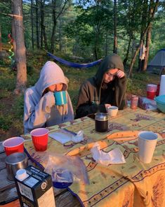 two people sitting at a picnic table in the woods