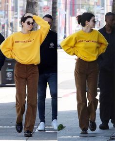 a woman in a yellow shirt and brown pants walking down the street