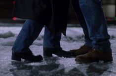 two people standing next to each other in the snow with their feet on one another