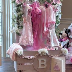 a baby crib with pink and white clothes on display in front of a window