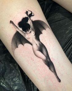 a black and white photo of a woman with a bat tattoo on her leg