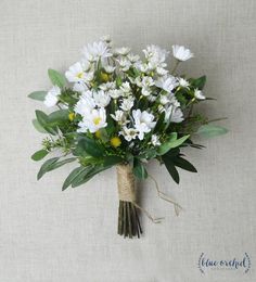 a bouquet of white daisies tied to a burlock with green leaves and twine