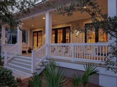 the front porch of a house with white railings and steps leading up to it