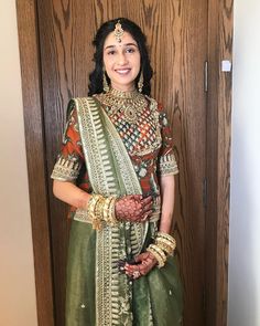 a woman in a green and gold outfit standing next to a wooden door with her hands on her hips