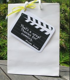 a white paper bag with a black and white movie clapper tag attached to it