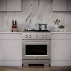 a stove top oven sitting inside of a kitchen next to a counter with utensils on it