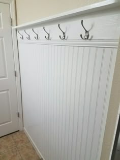 there is a coat rack with hooks on the wall next to a door and tile floor